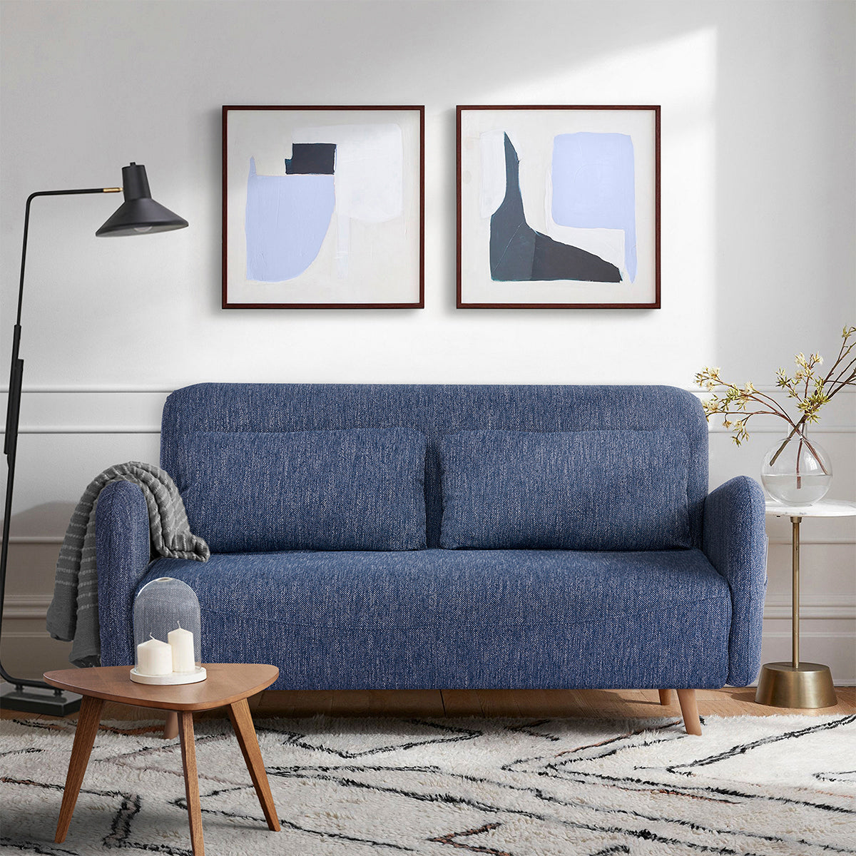 Canapé-lit BZ en tissu bleu chiné dans un salon moderne, avec accoudoirs arrondis, pieds en bois naturel et coussins assortis. Solution pratique et élégante pour un couchage d’appoint dans un intérieur chaleureux.