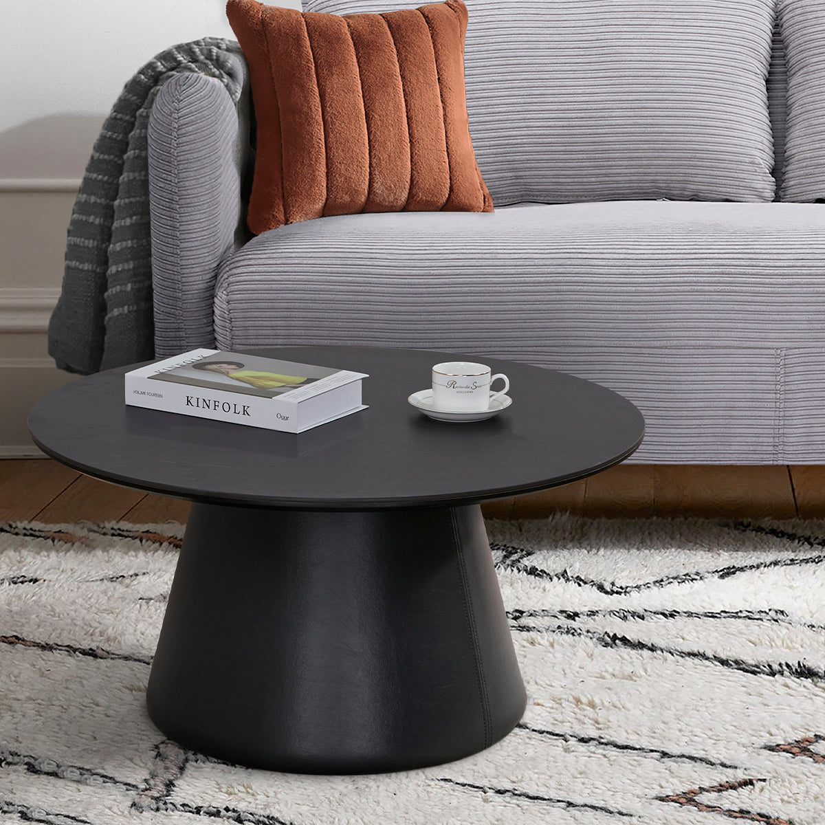 Vue d’ambiance de la table basse ronde MANDY diamètre 80 cm en finition imitation marbre noir stratifié avec le canapé-lit BZ ARI en finition tissu velours côtelé